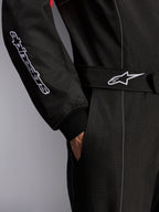 Mono Alpinestars KMX-9 V3, mono de karting, negro, rojo y blanco, detalle en primer plano del cinturón ajustable con logo de estrella y manga con marca bordada, con costuras de contraste blancas y bolsillo lateral.
