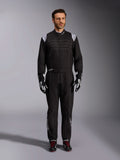 Mono Alpinestars KMX-9 V3, traje de karting negro y blanco, vista de cuerpo completo en un modelo, con logotipos y detalles blancos en los hombros, combinado con guantes de carreras en blanco y negro y calzado negro con cordones rojos, ajuste atlético-regular para equipamiento de karting profesional.