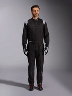 Mono Alpinestars KMX-9 V3, traje de karting negro y blanco, vista de cuerpo completo en un modelo, con logotipos y detalles blancos en los hombros, combinado con guantes de carreras en blanco y negro y calzado negro con cordones rojos, ajuste atlético-regular para equipamiento de karting profesional.