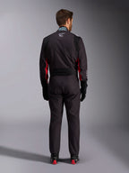 Mono Alpinestars KMX-9 V3 Graphic 3, traje de karting, negro y rojo, vista posterior con el panel elástico lumbar y la etiqueta de certificación FIA en el cuello, combinado con guantes de carreras negros y botas con detalles rojos