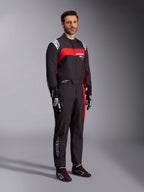Modelo masculino con el mono Alpinestars KMX-9 V3 Graphic 3, traje de karting negro y rojo, con hombreras blancas y logotipo rojo en el pecho, combinado con guantes de carreras negros y calzado con cordones rojos, ropa profesional de automovilismo.