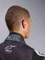 Traje Alpinestars KMX-9 V3 Graphic 3, primer plano de la zona posterior del cuello, mostrando la etiqueta de homologación FIA 8877-2022 Grado 1 y el logotipo blanco KMX-9 sobre material negro, detalle de equipamiento de competición para karting