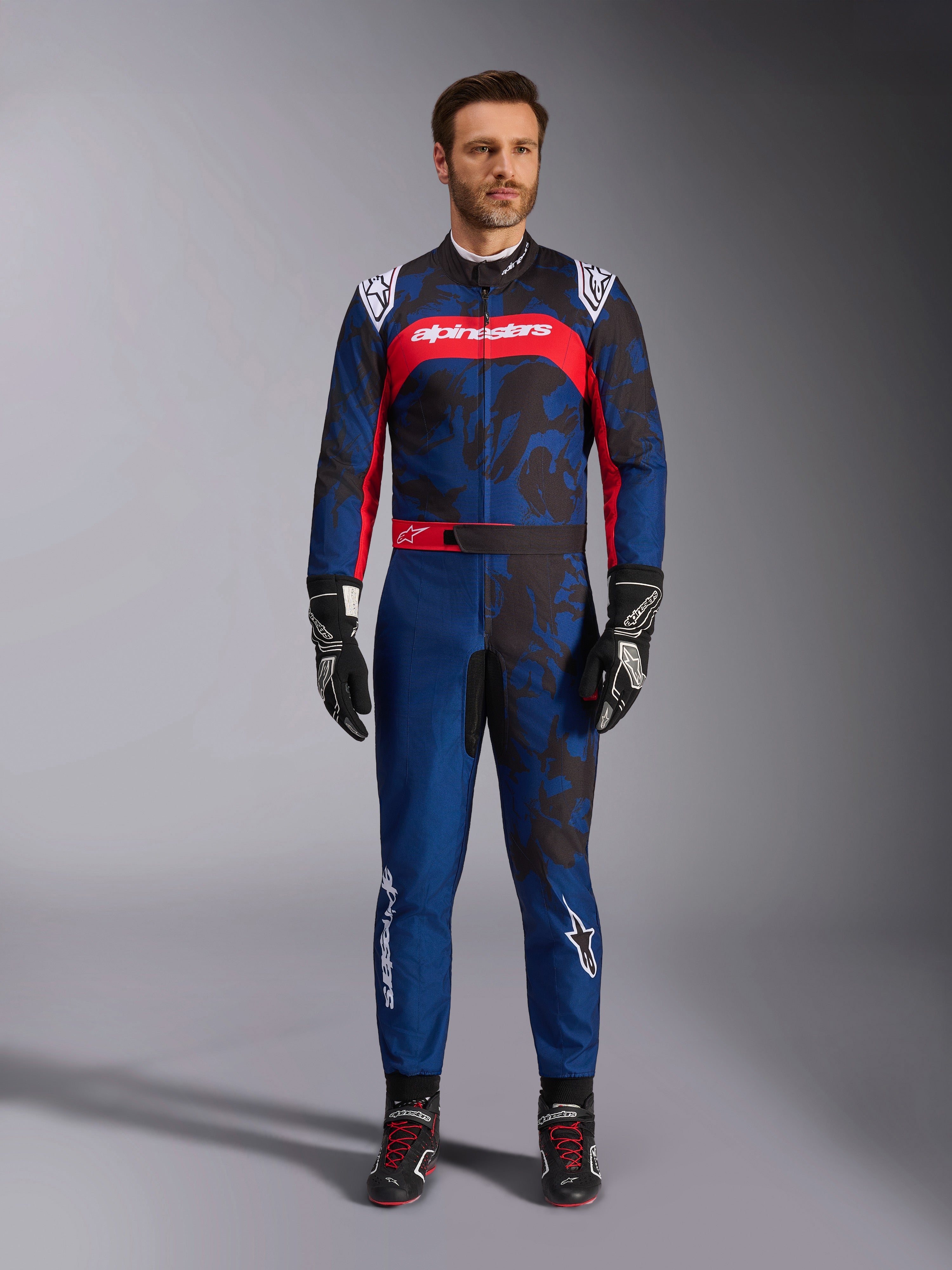 Alpinestars KMX-9 V3 Graphic 5 Suit, Karting Suit in Navy and Red, featuring an abstract camo-style graphic pattern, worn by a model with black racing gloves and shoes, athletic design with prominent Alpinestars branding on the chest and legs.