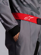 Alpinestars KMX-9 V3 Graphic 5 Suit, mono de karting, gris oscuro y negro con cinturón rojo, primer plano del cinturón ajustable rojo con logo blanco, mano en el bolsillo del muslo y puño de punto negro sobre tela con diseño gráfico gris