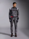 Alpinestars KMX-9 V3 Graphic 5 Suit, mono de karting, gris oscuro y negro con gráficos estilo camuflaje, con una banda negra en el pecho con logotipo blanco y un detalle de cinturón rojo, usado con guantes y calzado de carreras a juego, equipamiento profesional de automovilismo