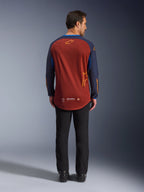 Alpinestars Maxdura Dual Jersey en marrón óxido y azul Mood Indigo, vista posterior que muestra el dobladillo trasero más largo y detalles del logotipo, usado con pantalones técnicos negros y botas, diseñado para motociclismo de aventura y dual-sport.