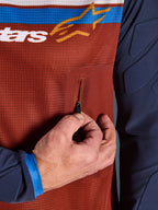 Detalle del jersey Alpinestars Maxdura Dual, torso de malla en color Rust Brown con bolsillo en el pecho con cremallera sin costuras, mangas Mood Indigo con acolchado integrado, detalle de jersey técnico de moto para aventura