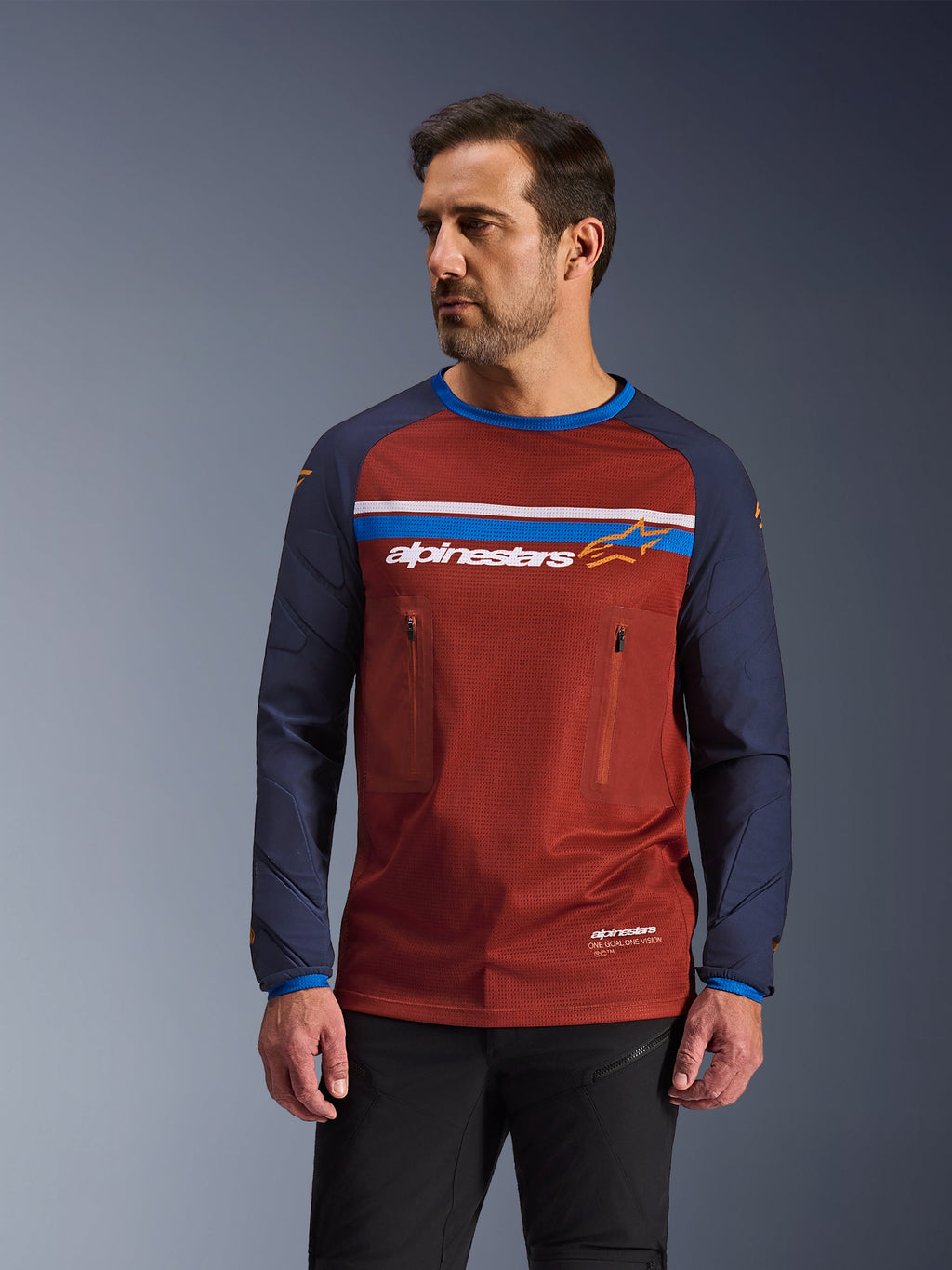 Alpinestars Maxdura Dual Jersey, jersey de motociclismo de aventura para hombre, marrón óxido y azul marino, con bolsillos dobles con cremallera en el pecho, franja horizontal con logotipo, torso de malla técnica y mangas de tejido resistente.