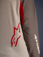 Alpinestars Maxdura Dual Jersey, Aluminum Walnut, vista de cerca que muestra el torso de malla ventilada con un logo de estrella roja y una manga marrón resistente a la abrasión con la marca Alpinestars en blanco, equipamiento técnico de moto para aventura y dual-sport