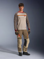Modelo luciendo el Alpinestars Maxdura Dual Jersey en color Aluminum Walnut, con torso de malla gris, mangas marrones con puños rojos y bolsillos con cremallera en el pecho, combinado con equipamiento off-road a juego para conducción de aventura.