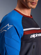 Alpinestars Maxdura Dual Jersey, jersey de motocross, gris oscuro y azul real, vista de primer plano que muestra el bolsillo con cremallera en el pecho, tejido de malla en el torso y acolchado integrado en la manga con el logo de la estrella
