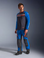 Alpinestars Maxdura Dual Jersey, gris oscuro y azul real, jersey de aventura para motocicleta con torso de malla y mangas azul real, usado por un modelo con pantalones de montar off-road a juego, con bolsillos con cremallera en el pecho y logotipo de Alpinestars.