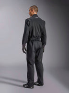 Alpinestars Kart Indoor V2 Suit, Black one-piece karting suit shown from a back three-quarter angle, featuring an elastic waist and a white logo on the neck, worn with black racing gloves and shoes, durable design for recreational karting