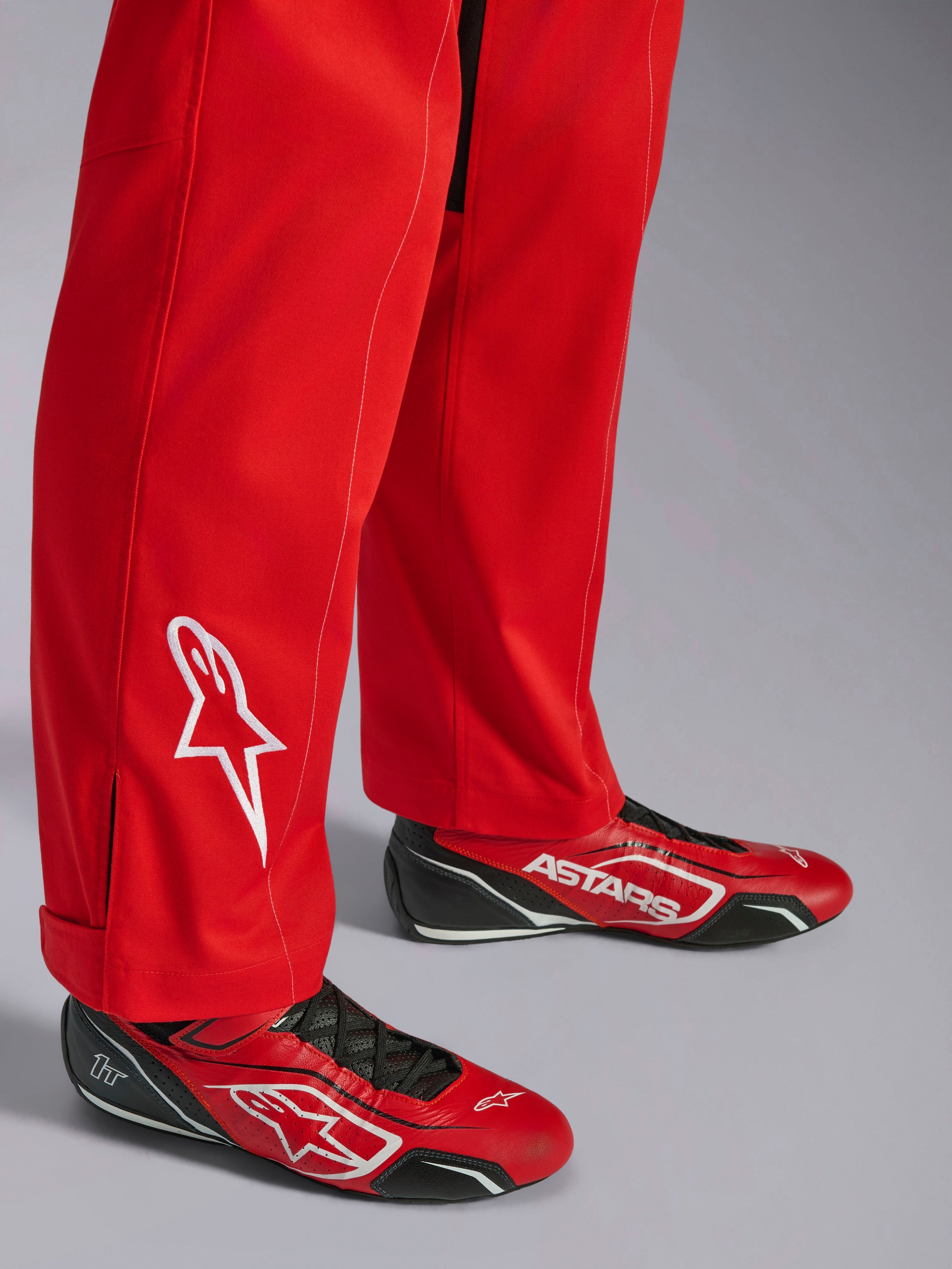 Mono Alpinestars Kart Indoor V2, rojo, detalle de la parte inferior de la pierna con logotipo de estrella bordado en blanco, usado con calzado de karting rojo y negro a juego, material de sarga de polialgodón de una sola capa para carreras recreativas