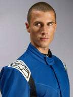 Mono Alpinestars Kart Indoor V2, mono de karting azul, vista de primer plano de modelo masculino, paneles blancos en los hombros con logotipo de estrella negro, cuello ergonómico, sarga duradera de una sola capa para carreras recreativas.