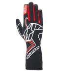 Guantes Alpinestars Tech-1 Race V4, guantes de carreras para automovilismo, negros con detalles rojos y blancos, gran logotipo de estrella blanca en el dorso, refuerzos rojos en los dedos, marca blanca en el puño largo extendido y patrones de diseño geométrico.