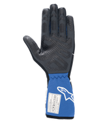 Guantes Alpinestars Tech-1 Race V4, negro y azul, vista interior de la palma que muestra el patrón de agarre de silicona texturizada, puño azul extendido con etiqueta de certificación FIA y logotipo de Alpinestars en blanco, equipamiento profesional para automovilismo