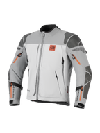 Chaqueta Alpinestars Nazca 3L GORE-TEX PRO, chaqueta de moto de aventura, gris oscuro y gris medio con detalles de cremalleras naranjas, logo All Terra en el pecho, refuerzos de Superfabric en hombros y codos, múltiples aberturas de ventilación con cremallera, diseño touring robusto