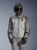 Chaqueta Alpinestars Nazca 3L GORE-TEX PRO, chaqueta de moto para aventura, gris oscuro y gris medio con acentos de cremalleras naranjas, usada con pantalones a juego y casco negro, con una construcción textil duradera y logotipos visibles de GORE-TEX PRO y All Terra