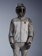 Chaqueta Alpinestars Nazca 3L GORE-TEX PRO, chaqueta de moto para aventura, gris oscuro y gris medio con acentos de cremalleras naranjas, usada con pantalones a juego y casco negro, con una construcción textil duradera y logotipos visibles de GORE-TEX PRO y All Terra