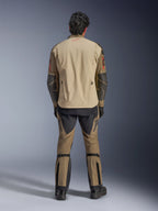 Alpinestars Nazca 3L GORE-TEX PRO Jacket en Walnut Rock Brown, vista trasera del piloto, que muestra los refuerzos de Superfabric en los codos y las cremalleras de ventilación traseras, combinada con pantalones de aventura a juego, botas negras y guantes, equipamiento técnico robusto para aventuras extremas.