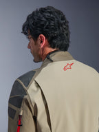 Chaqueta Alpinestars Nazca 3L GORE-TEX PRO, chaqueta de aventura en color Walnut Rock Brown, primer plano de la espalda y el hombro, logotipo de estrella roja en el cuello, paneles de refuerzo texturizados en gris, construcción textil duradera para conducción de motocicletas