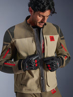 Chaqueta Alpinestars Nazca 3L GORE-TEX PRO, Walnut Rock Brown, chaqueta de moto de aventura con el frente abierto revelando el panel central de malla para el flujo de aire, logotipo All Terra en rojo, usada con guantes de moto GORE-TEX negros, equipamiento técnico para touring off-road