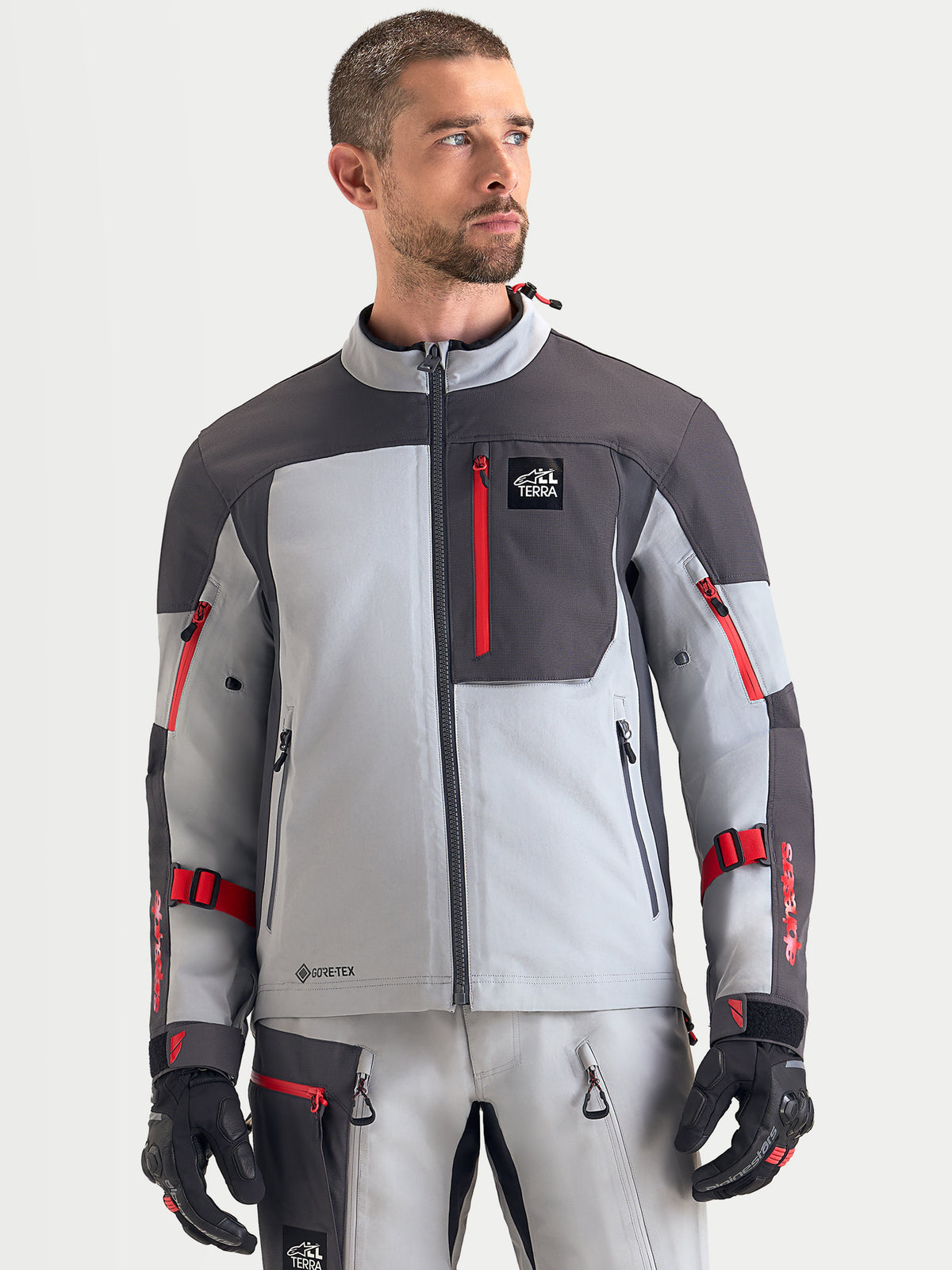 Alpinestars Arenis Gore-Tex Jacket, chaqueta de moto de aventura para hombre en gris medio, gris oscuro y negro, vista frontal en modelo que muestra construcción textil impermeable y bolsillo con cremallera en el pecho