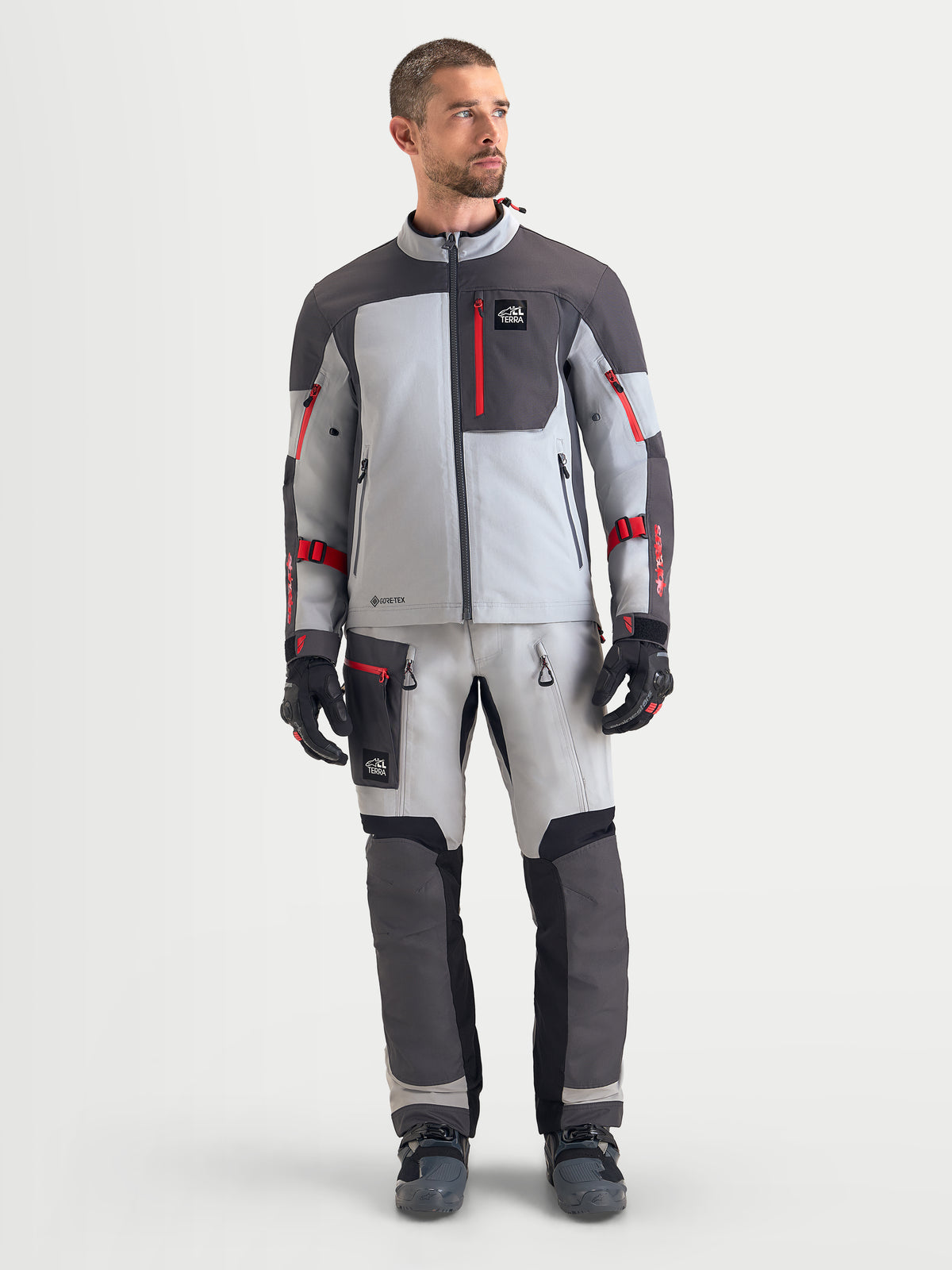 Chaqueta Arenis Gore-Tex Alpinestars, chaqueta de moto adventure para hombre, en gris medio, gris oscuro y negro, con construcción textil impermeable y detalles de cremallera en rojo, vista frontal en modelo