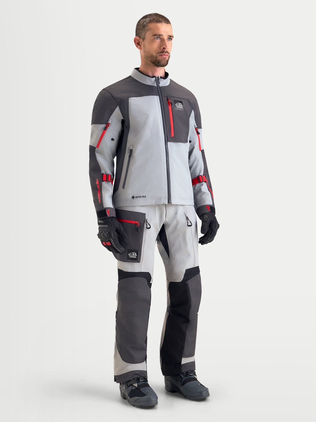 Alpinestars Arenis Gore-Tex Chaqueta, chaqueta de moto de aventura para hombre en gris medio, gris oscuro y negro, mostrada con un modelo masculino que exhibe una construcción textil impermeable y equipamiento de moto a juego