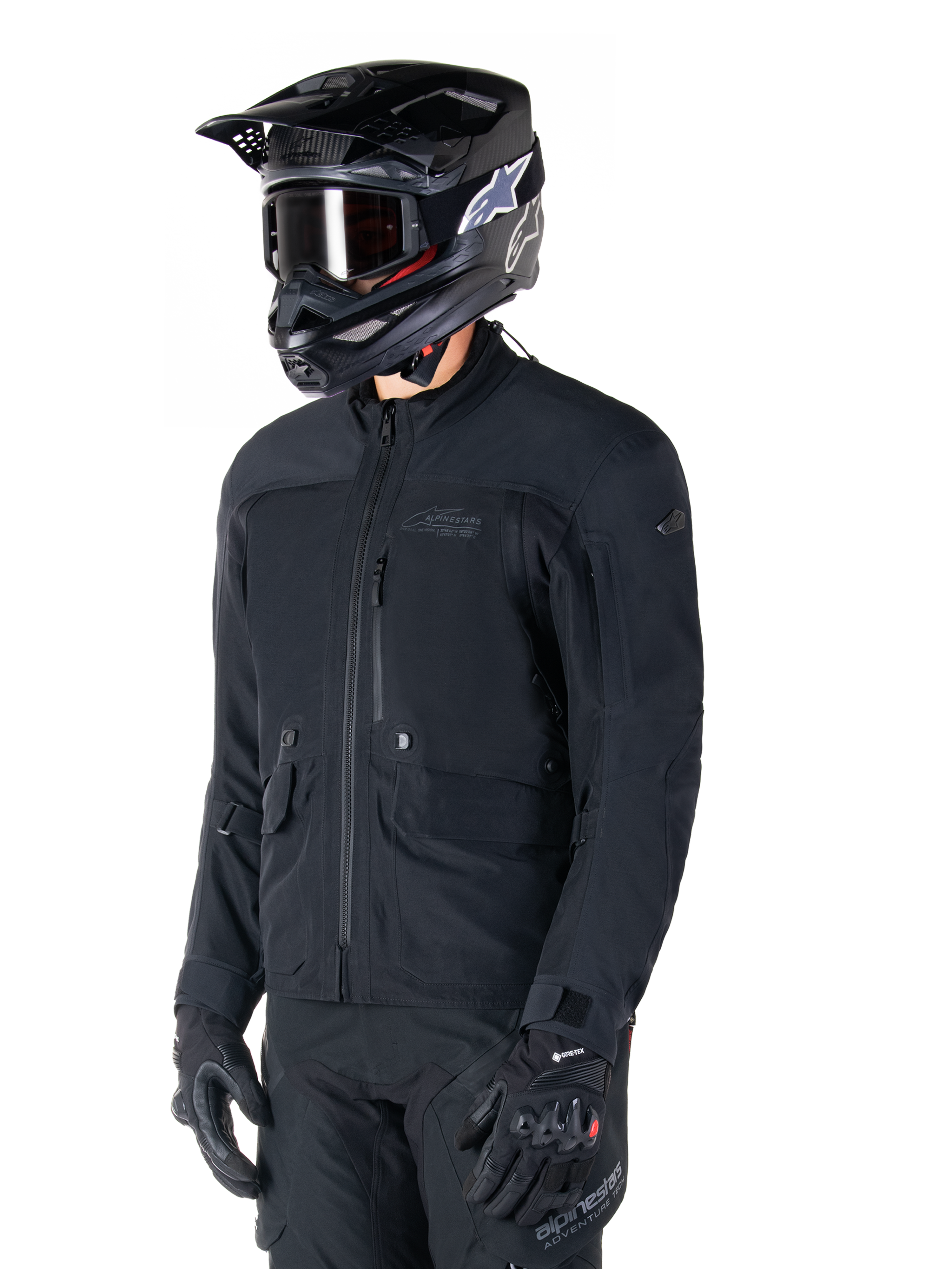 Alpinestars St-7 Prime GORE-TEX Jacket, Black motorcycle jacket, worn by a rider with a black helmet and goggles, featuring large chest cargo pockets and a laminated waterproof shell, premium adventure touring and commuting gear.
