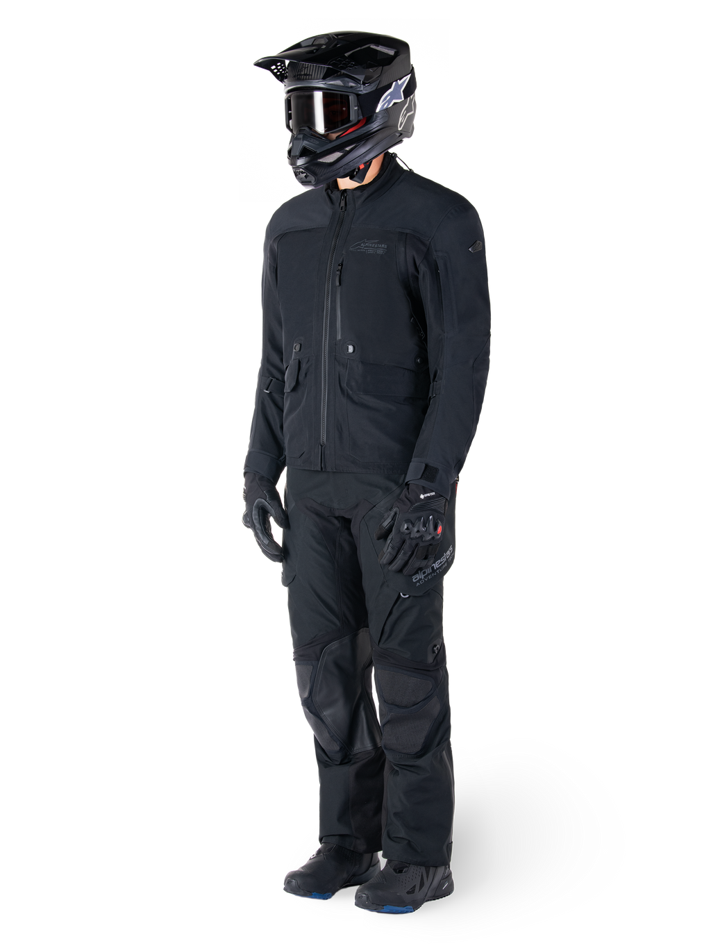 Motorcyclist wearing the Alpinestars St-7 Prime GORE-TEX Jacket in black, coordinated adventure touring outfit with matching black pants, black helmet with goggles, and gloves, featuring a streamlined and functional design for all-weather performance.