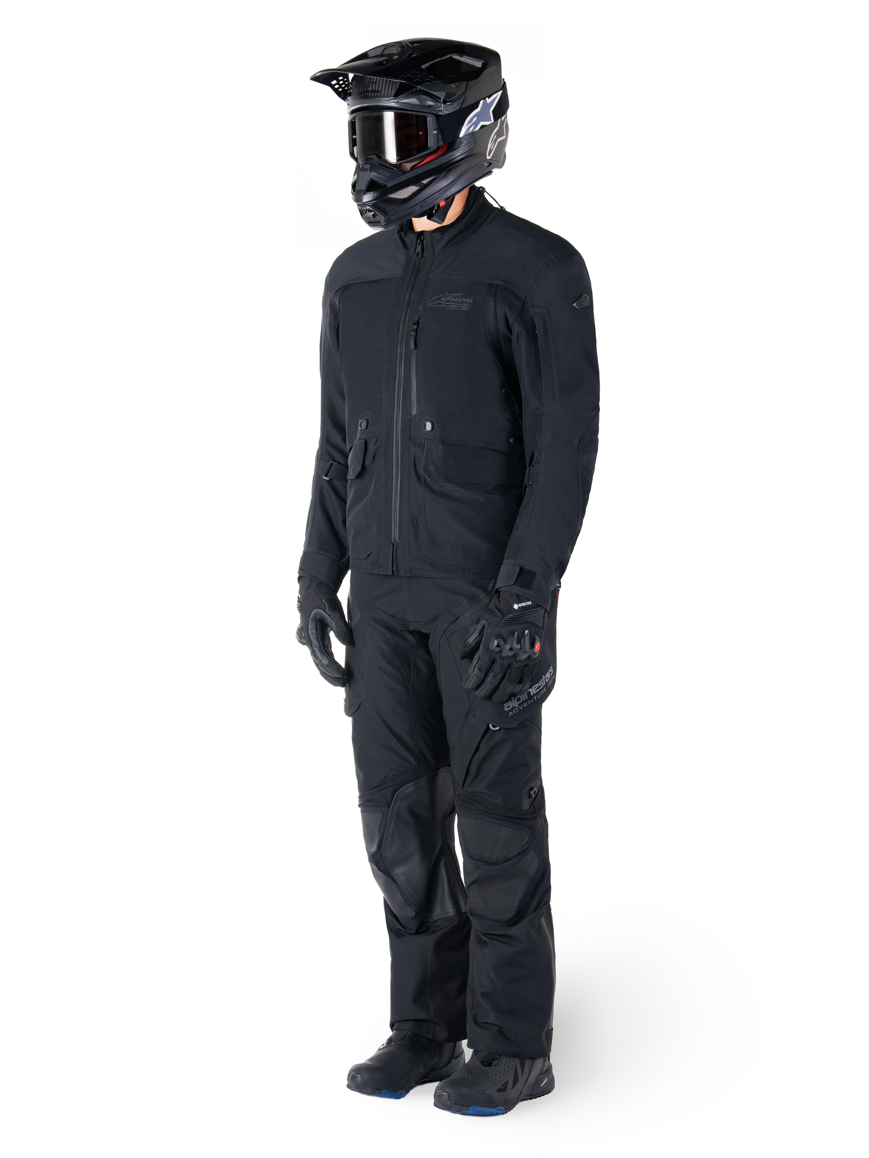Motorcyclist wearing the Alpinestars St-7 Prime GORE-TEX Jacket in black, coordinated adventure touring outfit with matching black pants, black helmet with goggles, and gloves, featuring a streamlined and functional design for all-weather performance.