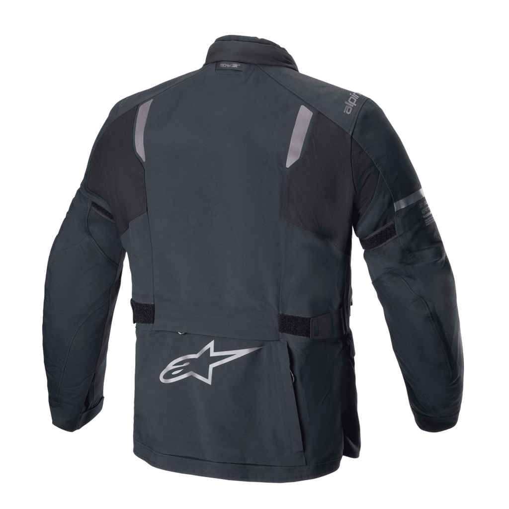 Chaqueta Alpinestars ST-7 2L GORE-TEX, vista trasera, negro y gris oscuro, con paneles reflectantes en los hombros, logotipo plateado de la estrella Alpinestars en la parte inferior de la espalda y correas de ajuste en la cintura, equipamiento de aventura para motociclismo