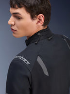 Chaqueta Alpinestars ST-7 2L GORE-TEX, chaqueta de motociclismo en negro y gris oscuro, vista de cerca del cuello que muestra el ajuste de cordón elástico y la etiqueta Tech-Air, con detalles reflectantes grises y logotipo de la marca en el hombro.