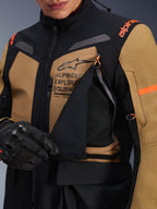 Alpinestars ST-7 2L GORE-TEX Jacket, Adventure Touring Motorcycle Jacket, Gobi Brown and Black, close-up showing the unzipped chest ventilation panel revealing breathable mesh, featuring Alpinestars Exploration Equipment branding and orange accents.