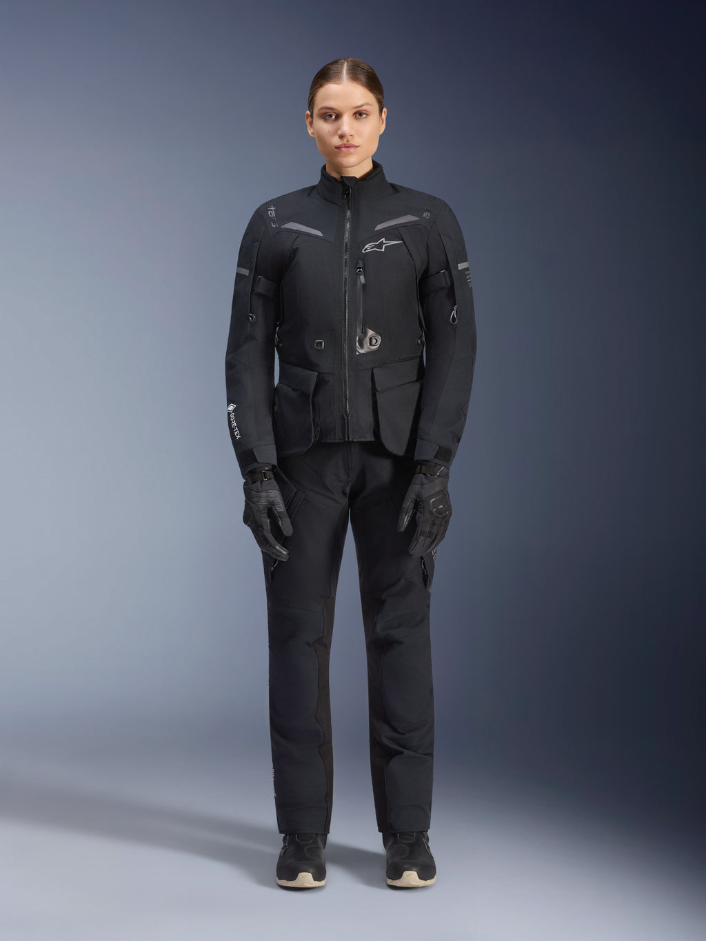 Alpinestars Stella ST-7 2L GORE-TEX Jacket, Women's Motorcycle Touring Jacket, Black and Dark Gray, worn with matching riding pants and gloves, featuring waterproof laminated shell, reflective accents, and ergonomic adventure design
