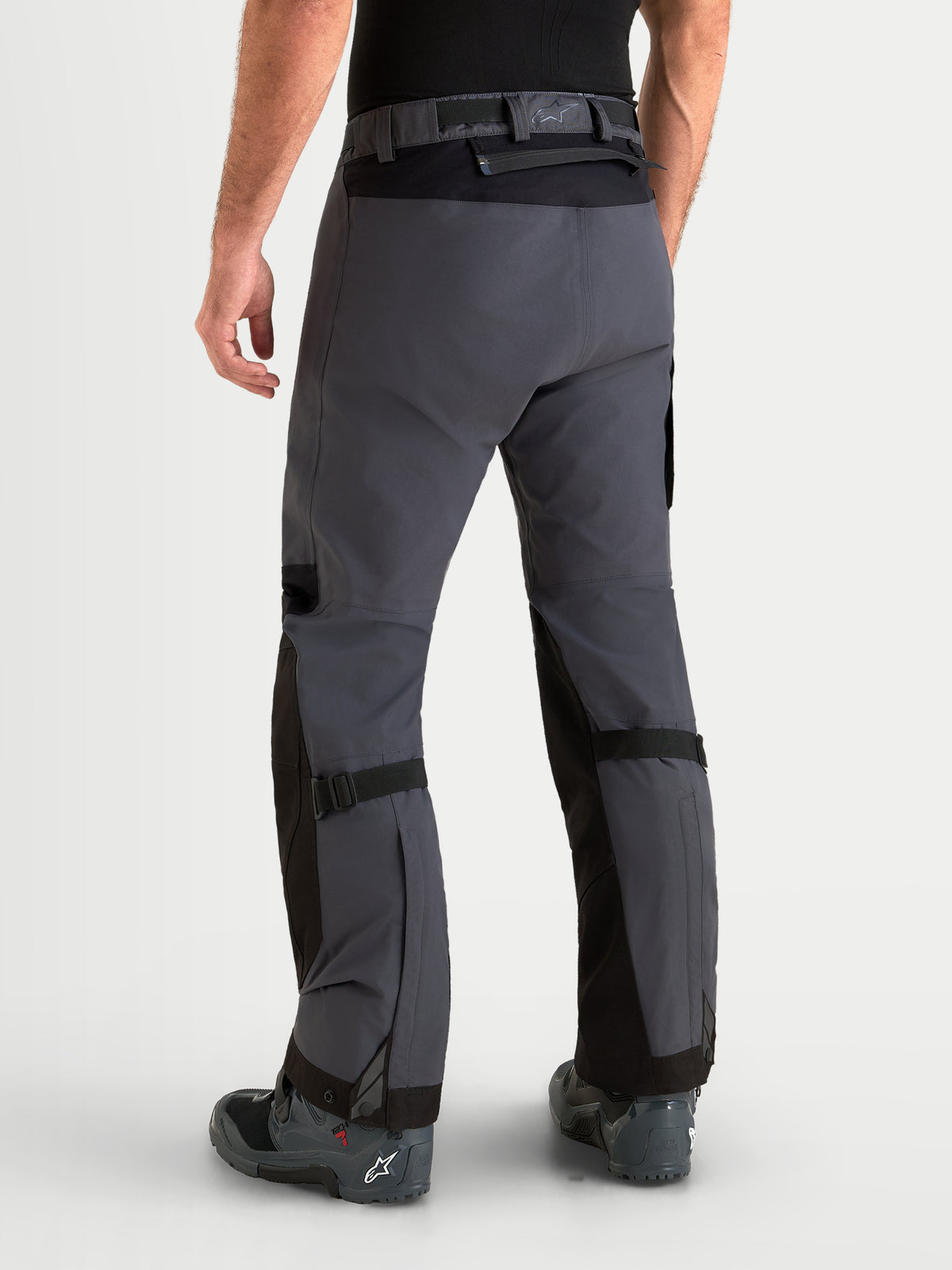 Alpinestars Arenis Gore-Tex Pantalones, pantalones de moto para aventura para hombre, en negro y gris oscuro, vista trasera en un modelo que muestra la construcción textil impermeable y el cierre de la cintura