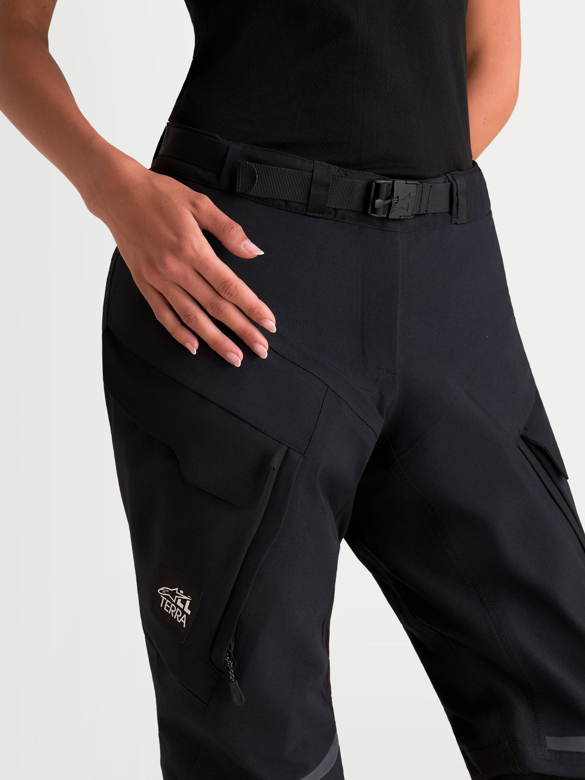 Alpinestars Stella St-7 V2 2L Gore-Tex Pants, women's adventure touring motorcycle pants, black, close-up view showing magnetic waist closure, integrated belt, and waterproof cargo pockets worn by a model