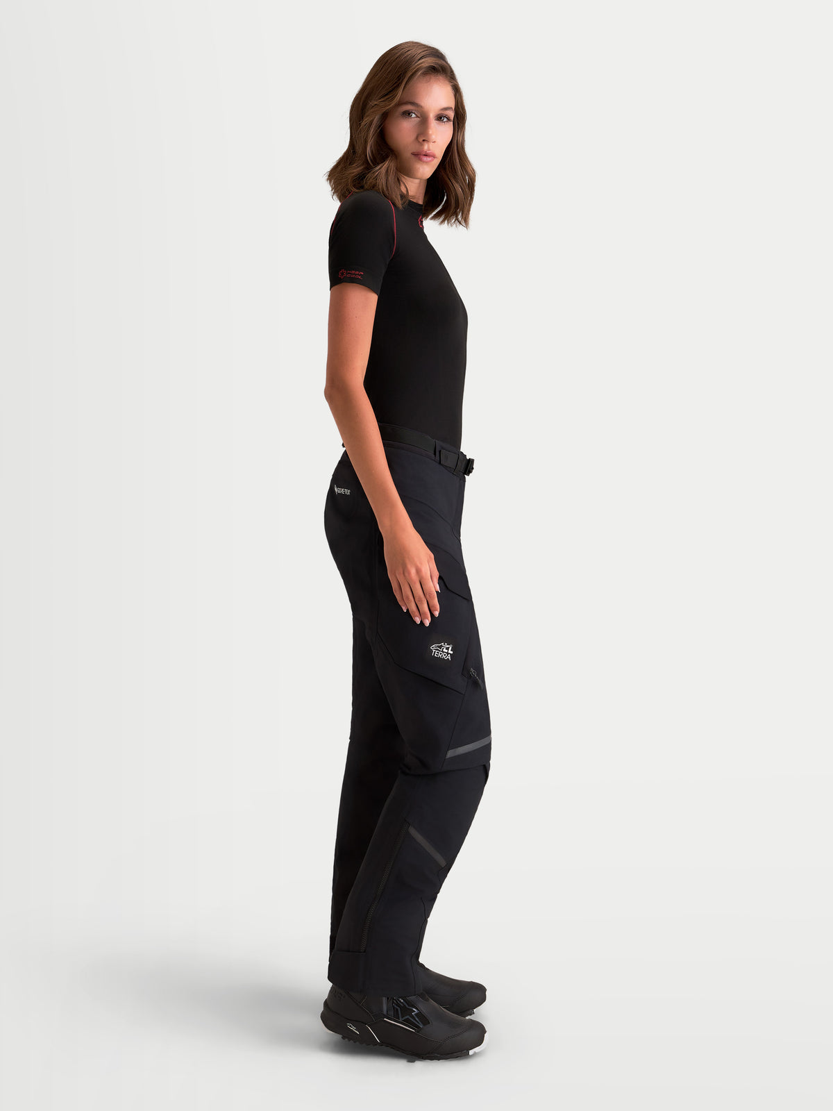 Alpinestars Stella St-7 V2 2L Gore-Tex Pants, women's adventure touring motorcycle pants in black, side profile view worn by a model, featuring waterproof GORE-TEX construction and cargo pockets.