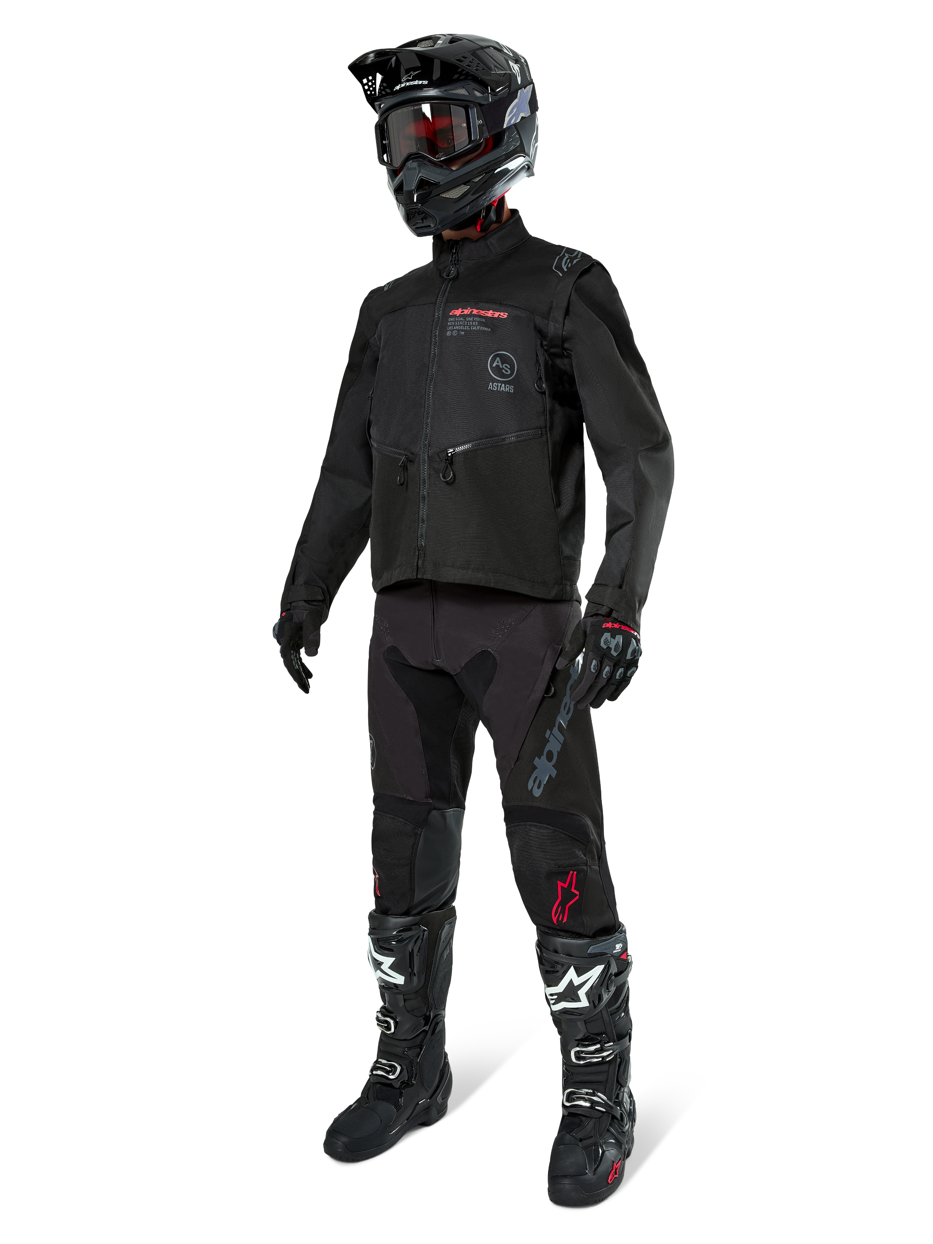 Piloto de motocross con equipamiento completo de carreras, chaqueta Alpinestars Pro-Dura en negro, pantalones negros con logotipos grises y detalles rojos, casco negro con gafas, y botas de motocross en blanco y negro, conjunto coordinado para enduro y conducción off-road
