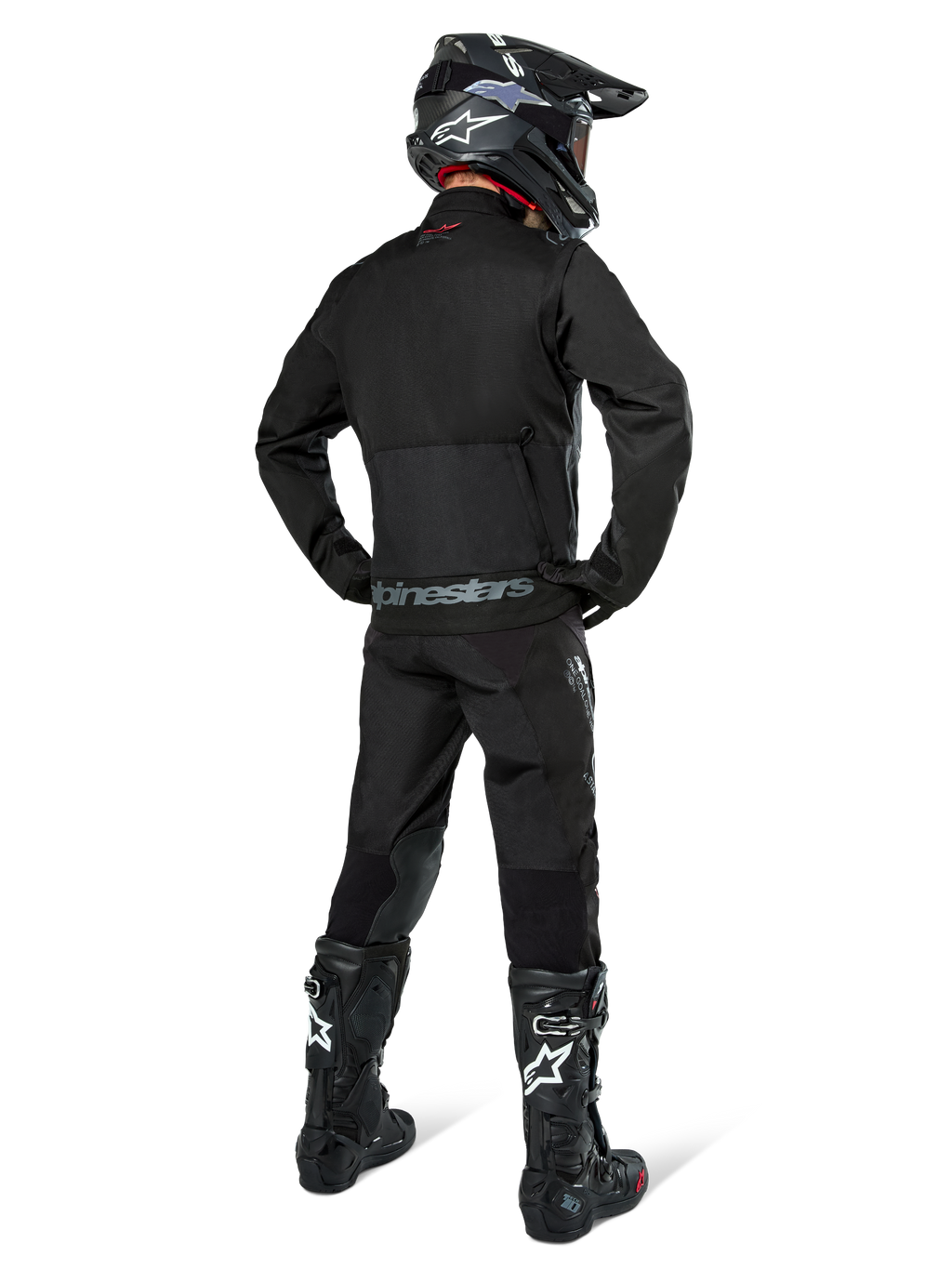 Chaqueta Alpinestars Pro-Dura, chaqueta de enduro off-road en color negro, vista trasera combinada con pantalones a juego y botas Tech 10 negras, con el logotipo de Alpinestars destacado en la parte inferior de la espalda, material textil robusto para conducción agresiva en senderos.