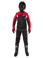 Piloto de motocross con equipamiento completo para off-road, chaqueta Alpinestars Pro-Dura en negro, rojo brillante y blanco, pantalones negros con detalles rojos, casco negro con gafas rojas, botas negras y blancas, atuendo coordinado para enduro y trail