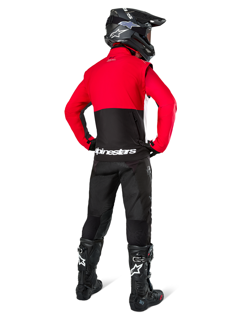 Piloto de motocross visto desde atrás vistiendo la chaqueta Alpinestars Pro-Dura en negro, rojo brillante y blanco, combinada con pantalones negros, casco negro y botas off-road negras, con una sección superior roja y una inferior negra con la marca Alpinestars en blanco en la espalda.