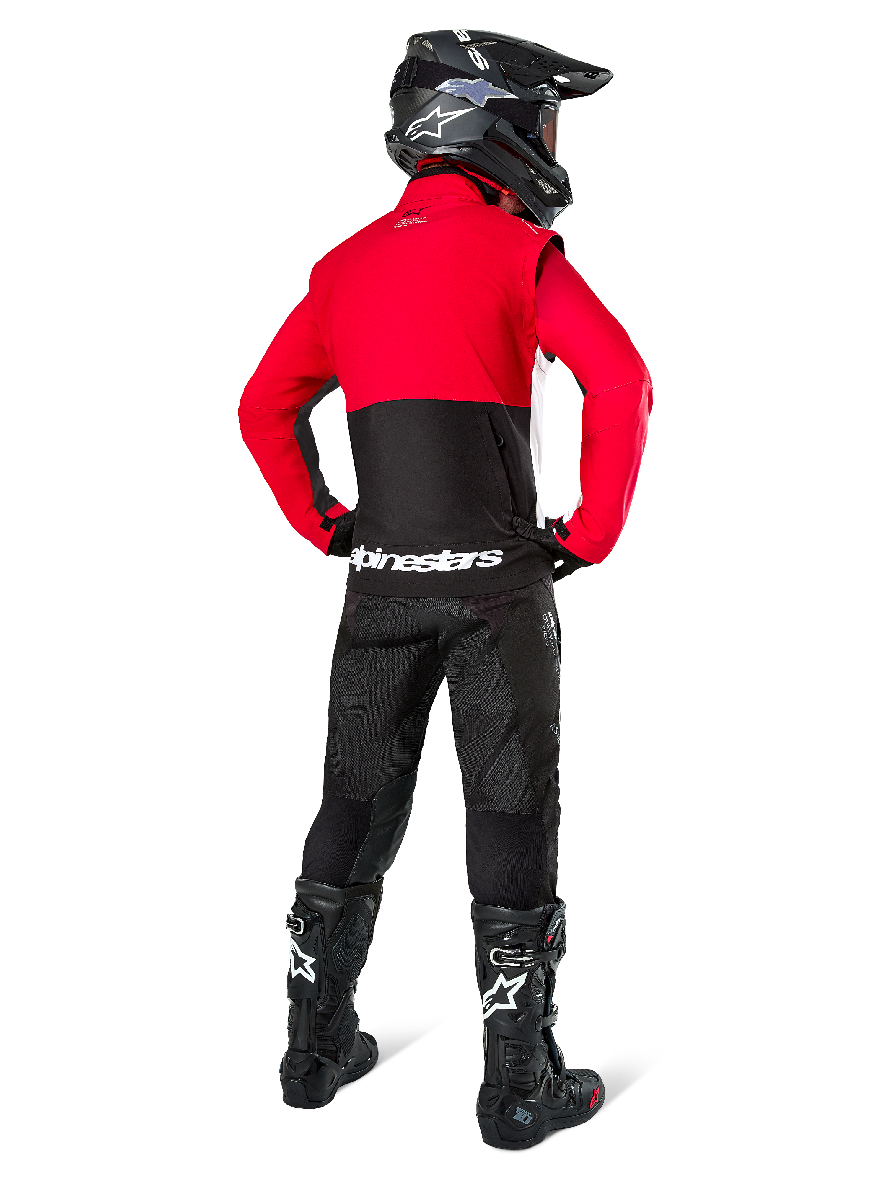 Piloto de motocross visto desde atrás vistiendo la chaqueta Alpinestars Pro-Dura en negro, rojo brillante y blanco, combinada con pantalones negros, casco negro y botas off-road negras, con una sección superior roja y una inferior negra con la marca Alpinestars en blanco en la espalda.