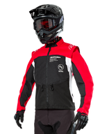 Chaqueta Alpinestars Pro-Dura, chaqueta de moto para enduro y off-road, negra con bloques de color rojo brillante y blanco, usada por un piloto con casco negro y gafas, con bolsillos delanteros con cremallera y logotipos de Alpinestars, construcción textil duradera para conducción en senderos