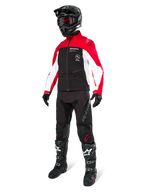 Piloto de motocross vistiendo la Chaqueta Softshell Lite-Dura de Alpinestars en negro, rojo brillante y blanco, con cuerpo negro y mangas rojas y blancas, combinada con pantalones negros, casco negro con gafas rojas y botas negras y blancas, equipamiento completo para carreras off-road.