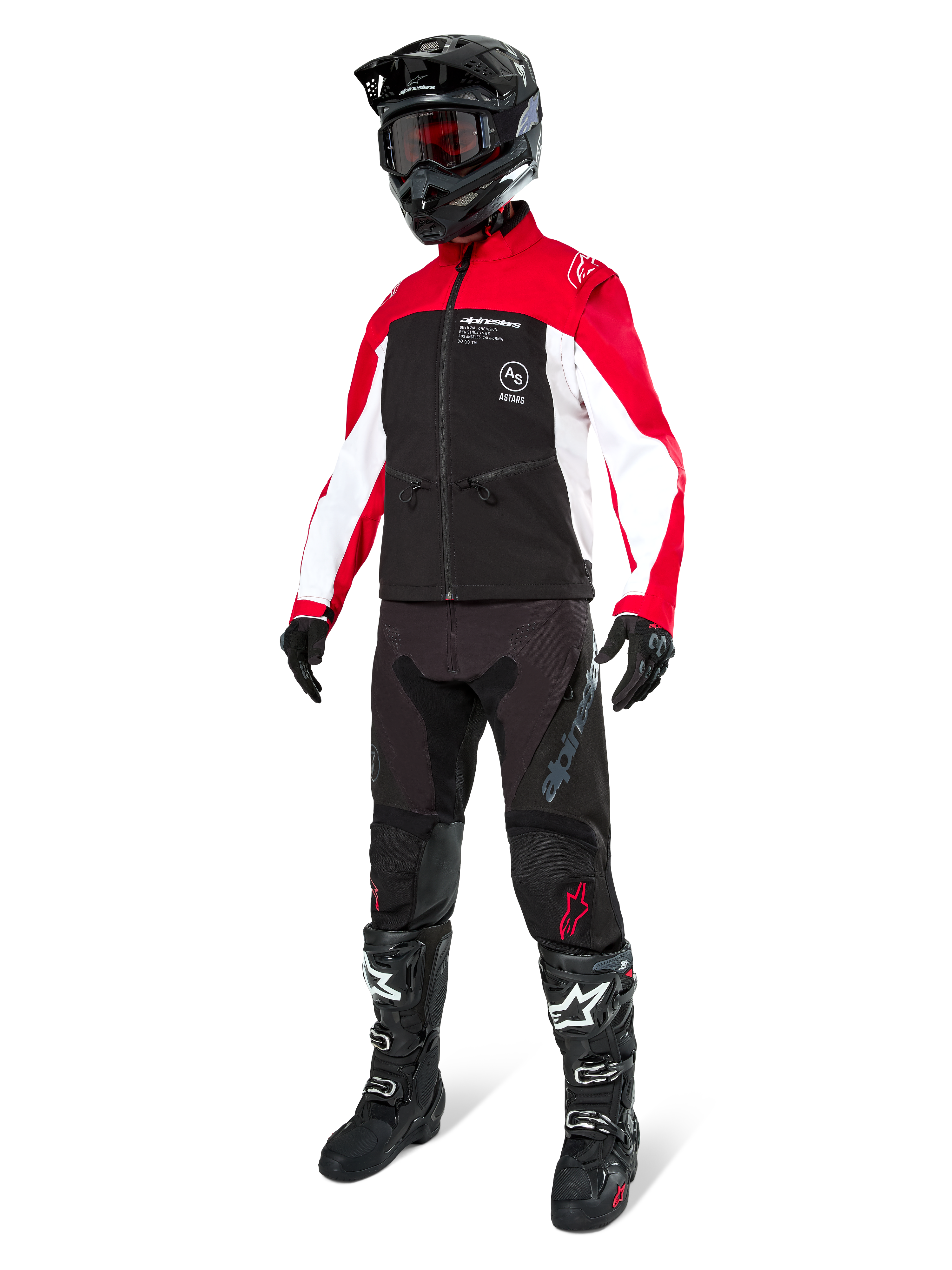 Piloto de motocross vistiendo la Chaqueta Softshell Lite-Dura de Alpinestars en negro, rojo brillante y blanco, con cuerpo negro y mangas rojas y blancas, combinada con pantalones negros, casco negro con gafas rojas y botas negras y blancas, equipamiento completo para carreras off-road.