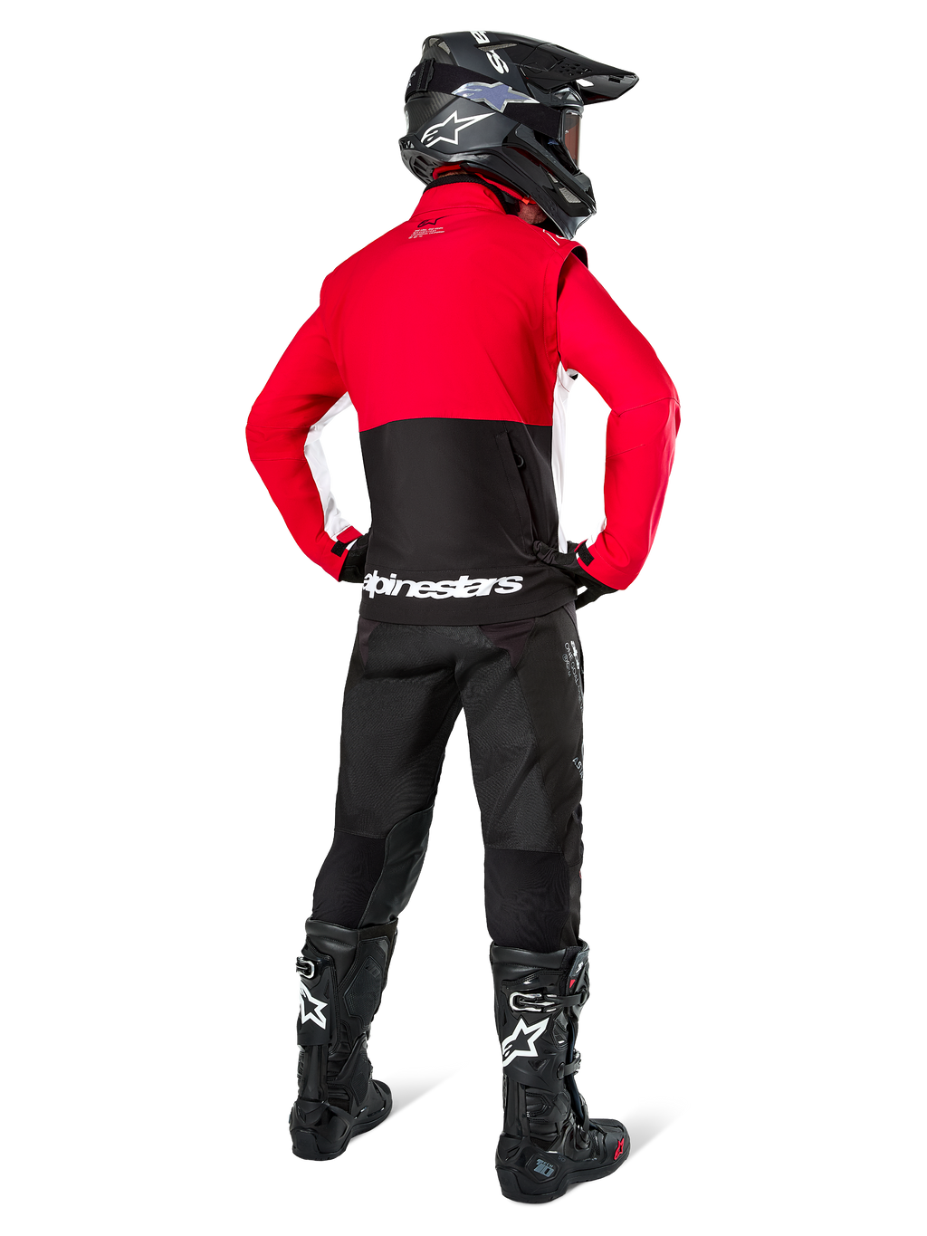 Piloto de motocross visto desde atrás con la Chaqueta Alpinestars Lite-Dura Softshell, negro, rojo brillante y blanco, con un panel superior rojo y sección inferior negra con logotipo blanco, combinado con pantalones negros, casco negro y botas negras, conjunto de enduro coordinado para conducción off-road