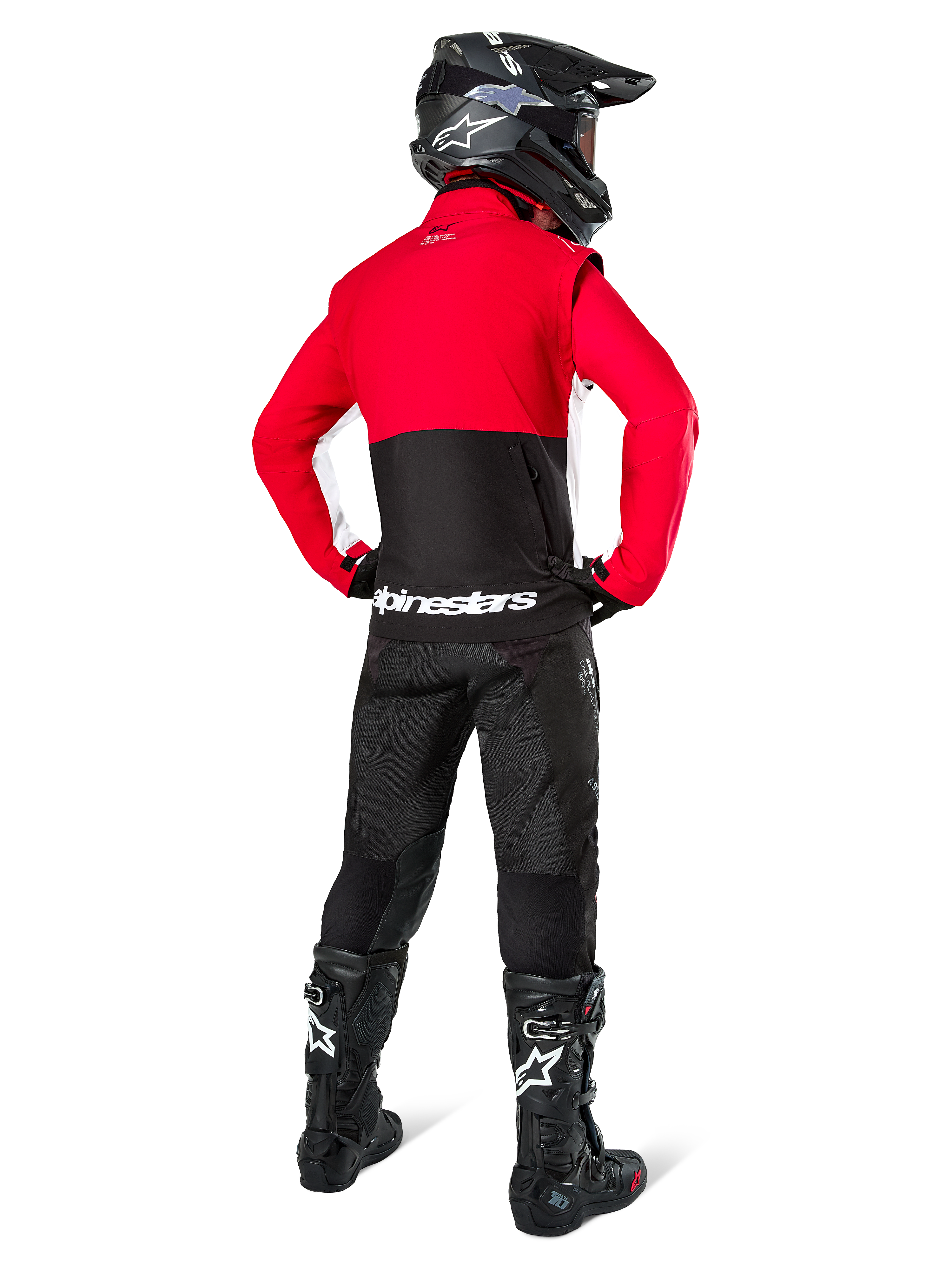 Piloto de motocross visto desde atrás con la Chaqueta Alpinestars Lite-Dura Softshell, negro, rojo brillante y blanco, con un panel superior rojo y sección inferior negra con logotipo blanco, combinado con pantalones negros, casco negro y botas negras, conjunto de enduro coordinado para conducción off-road